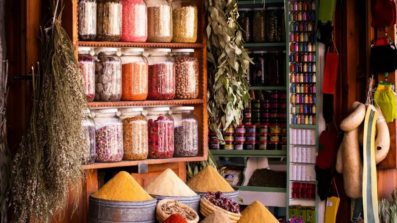 Colorful shop in Marrakech displaying dried flowers, herbs, and spices in baskets and jars.