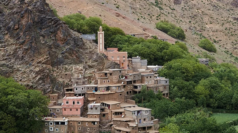 Lush Ourika Valley with Atlas Mountains in the background and traditional Berber villages.